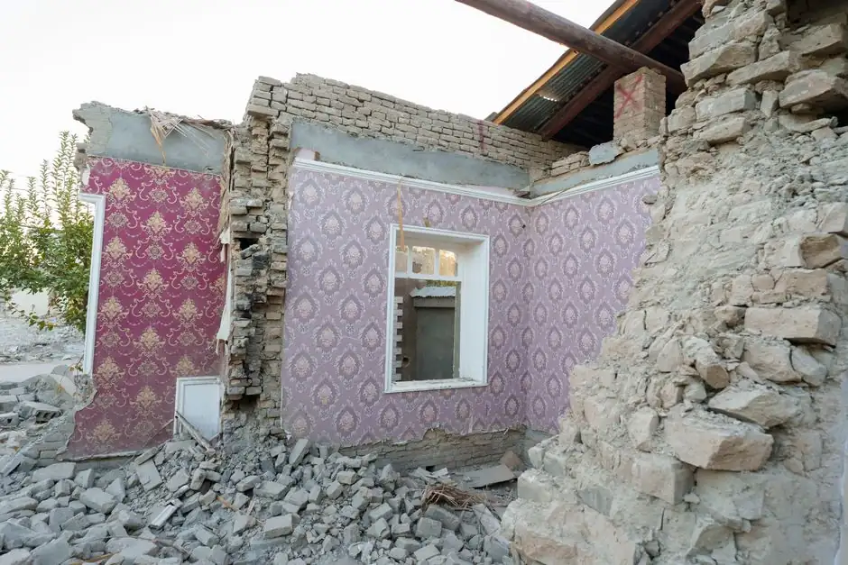 A damaged and abandoned house with visible wallpaper and rubble in Samarkand, Uzbekistan.